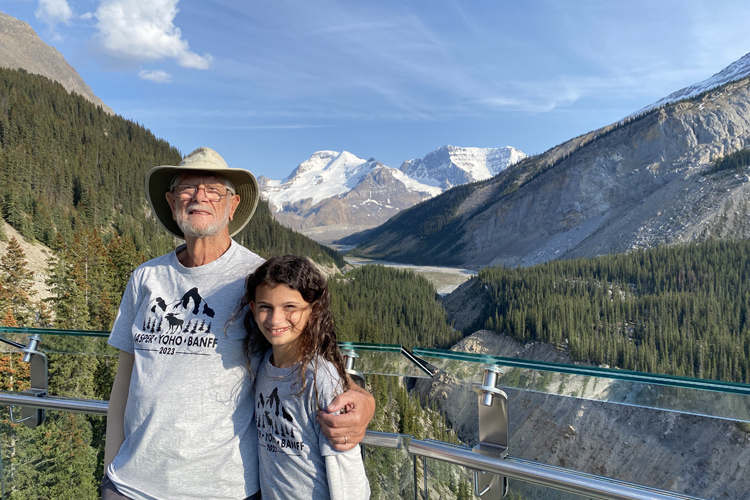 A grandfather enjoys the skywalk with his grand daughter.